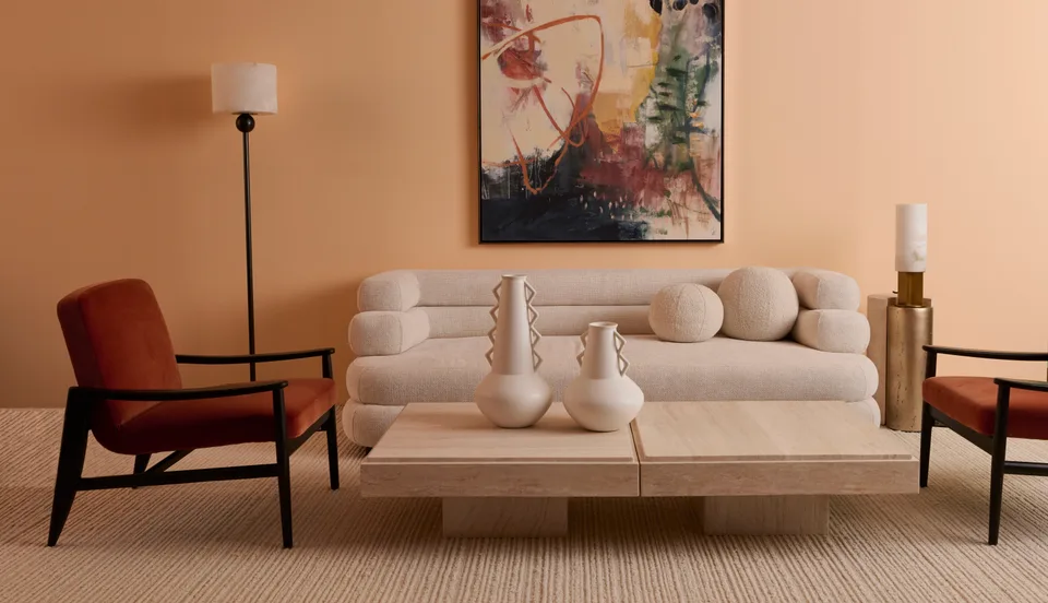 A living room set with peach walls, a cream sofa, an armchair and a low wooden table.