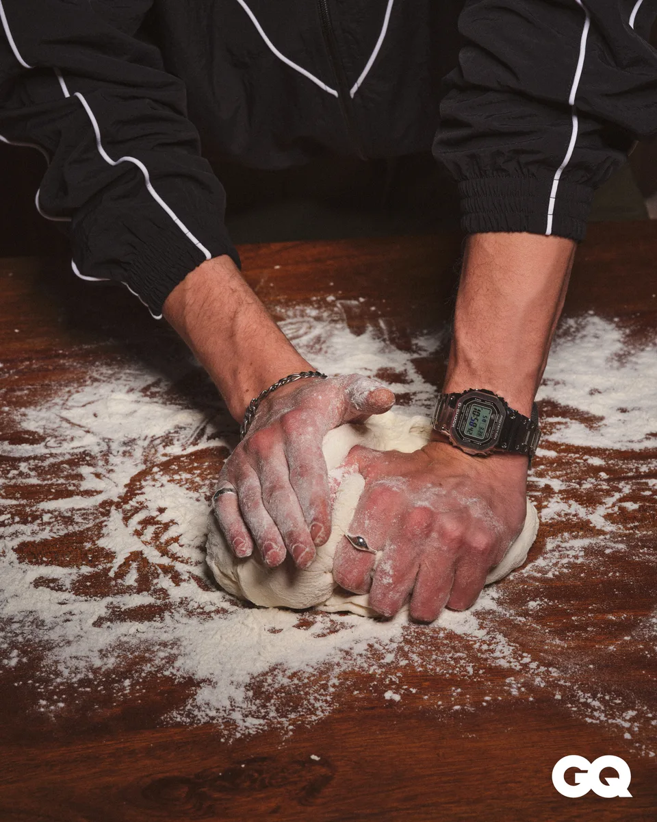 Hands knead dough on a flour-covered wooden surface, with a Casio watch on the wrist.