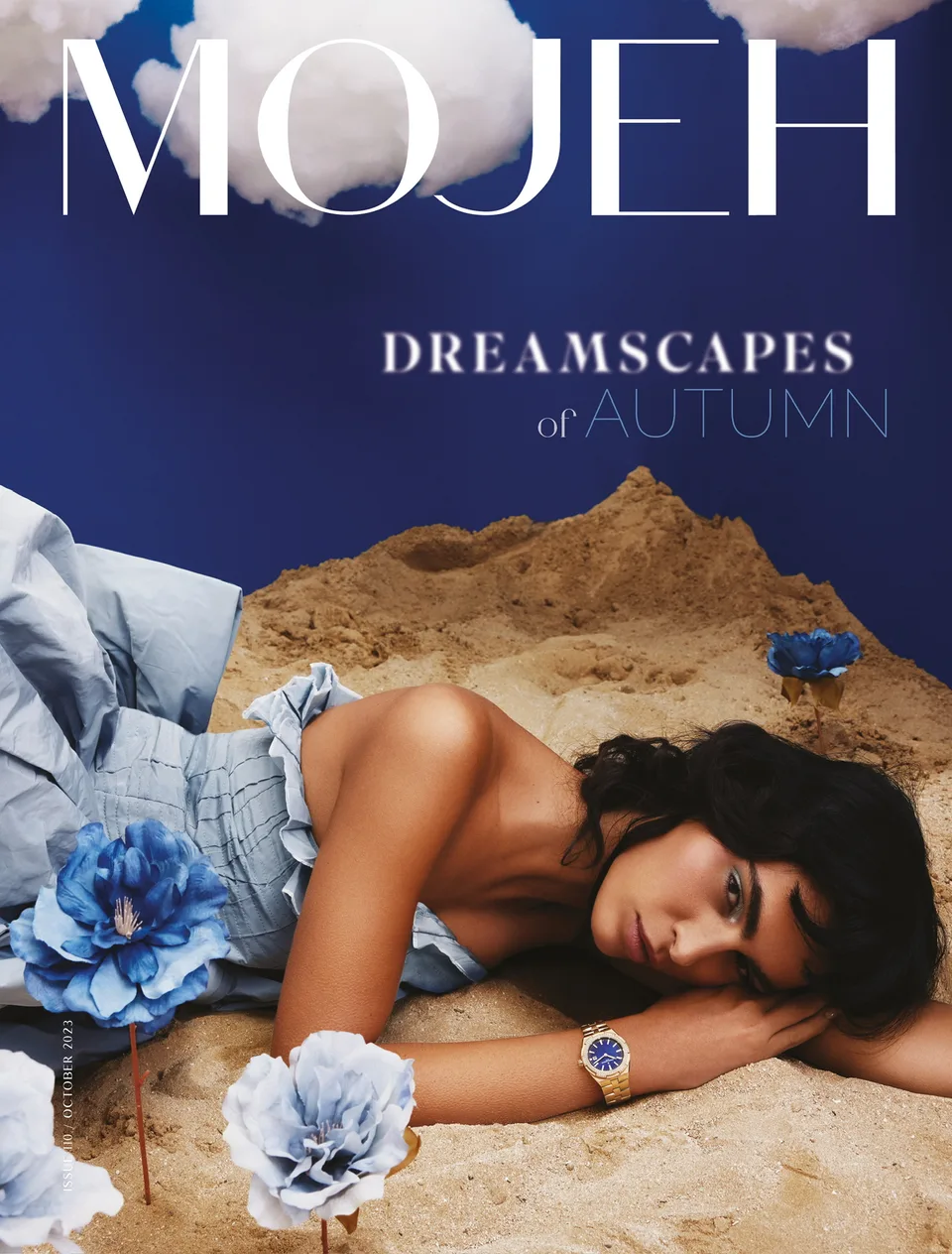 MOJEH Dreamscapes of Autumn cover with a model in a blue dress on sand beneath sculpted clouds