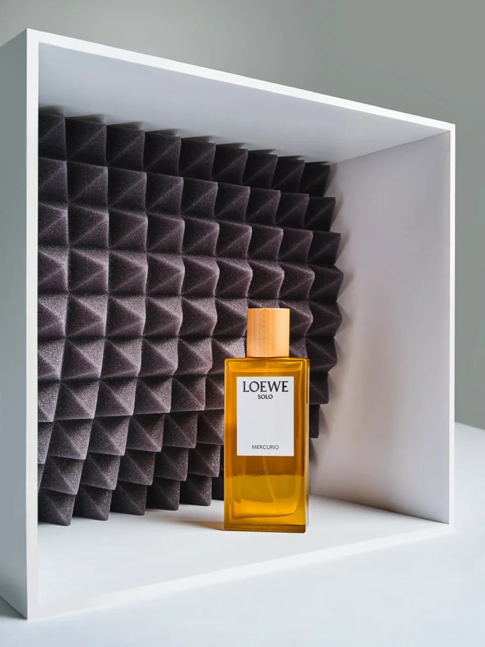 Loewe perfume bottle in a white display frame with a black folded backdrop