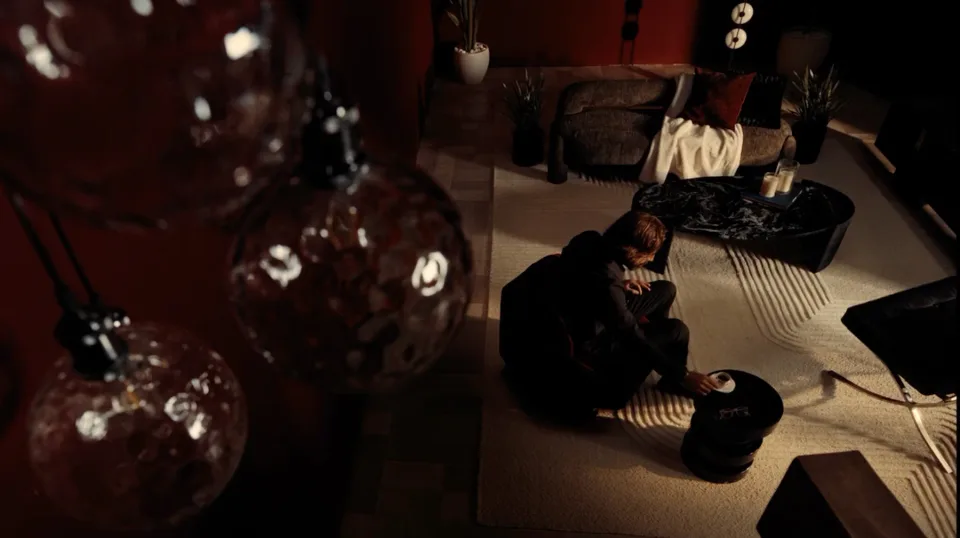 Overhead view of a person seated on the floor in a red-toned lounge.