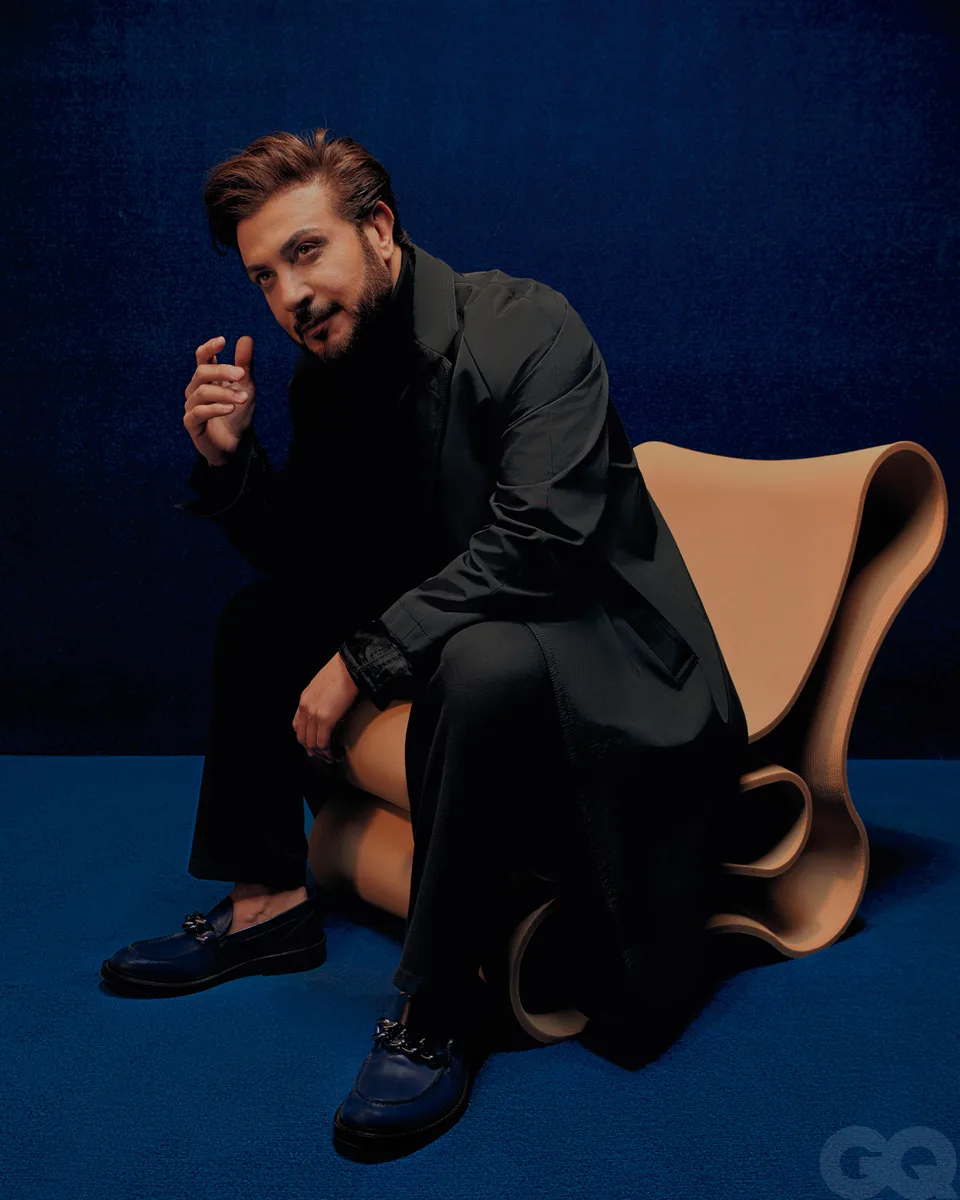 A seated portrait in a sculptural wooden chair on the blue set.