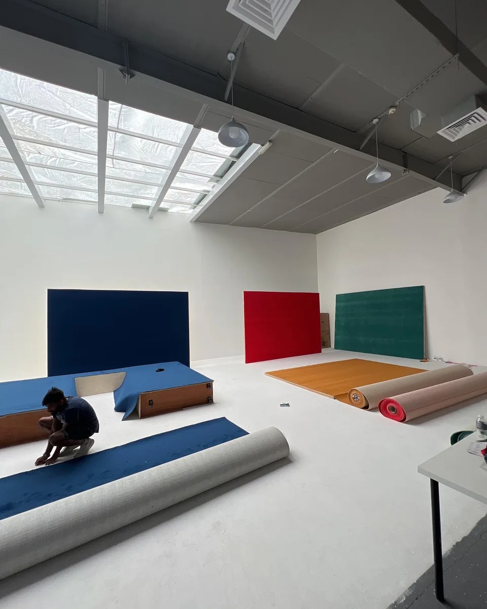 A crew member works on floor coverings in a studio with blue, red and green scenic walls.