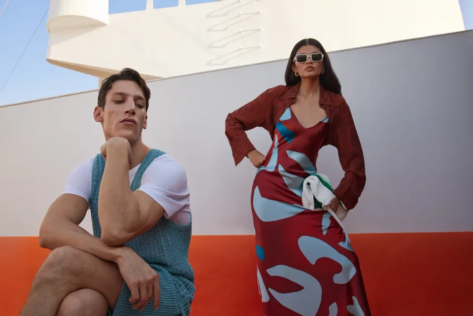 Two people against a white wall with an orange lower panel