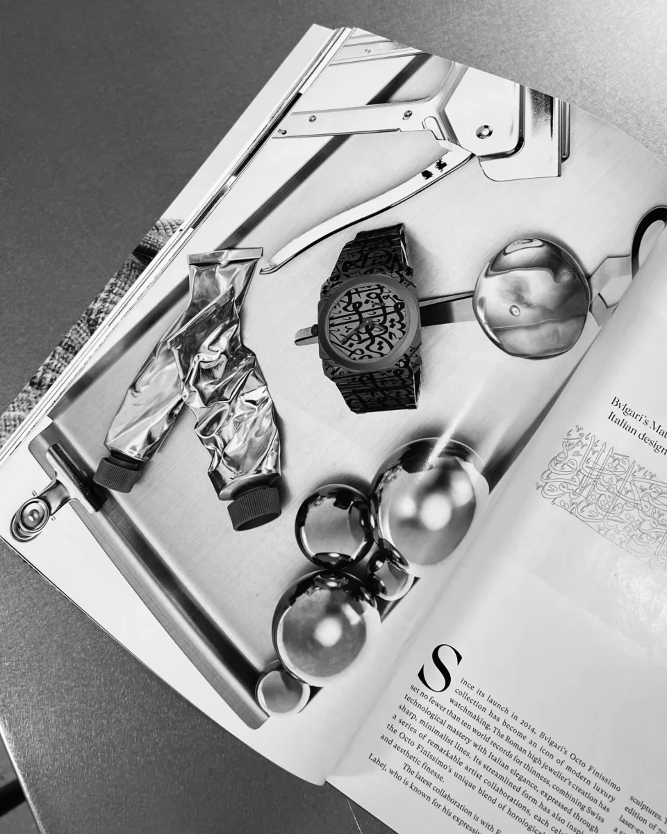 Open Bvlgari magazine spread featuring a watch and metallic objects