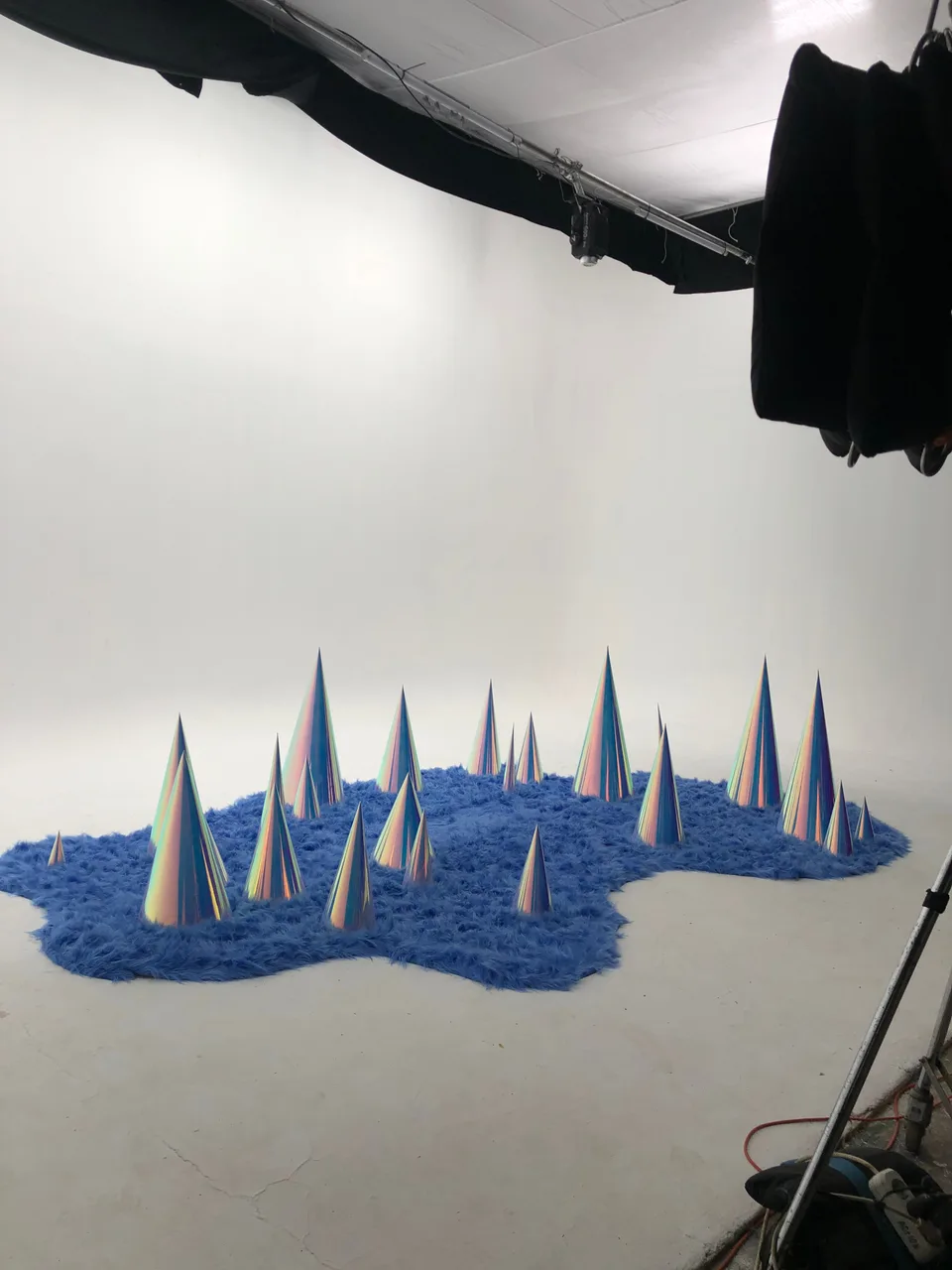 Blue textured flooring and reflective cones are arranged in the studio before the model steps in.