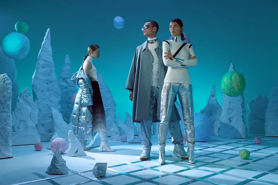 Two models stand between tall textured blue scenic forms.