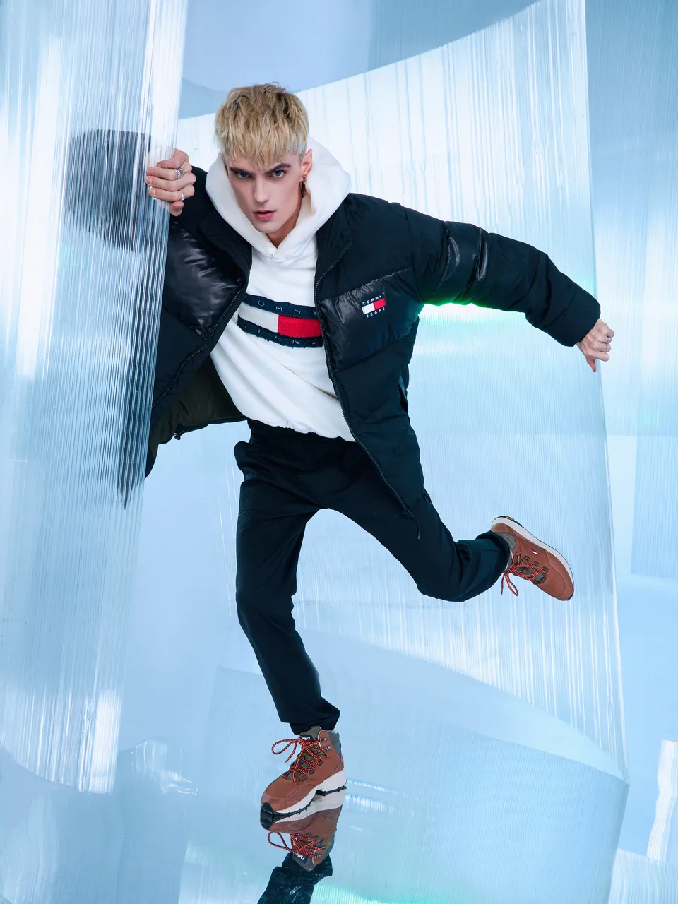 A model jumps in front of translucent curved walls on a reflective set.